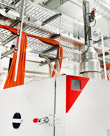 Battery test chamber from BINDER in a battery test laboratory with connected exhaust system and orange-colored cabling on the top of the unit.