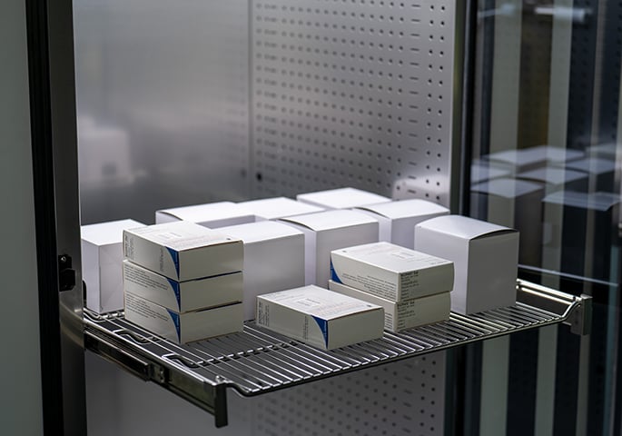 View inside an illuminated climate chamber containing pharmaceutical packaging.